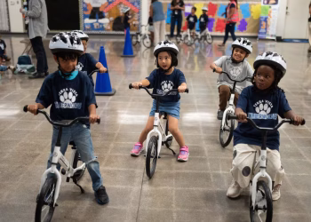 Un rito infantil se traslada al interior mientras los niños de jardín de infantes aprenden a andar en bicicleta en los gimnasios escolares